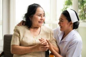 Beautiful nurse comforting female patient in the room.