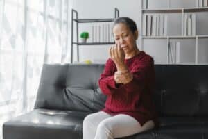 Elderly asian housewife woman sitting on sofa. wrist pain