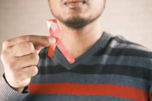 hand holding red HIV ribbon with copy space