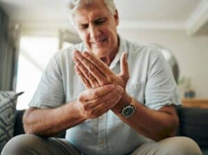 Hands, pain and arthritis with a senior man holding his hand while suffering from osteoporosis, cra