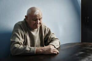 Pensive and thoughtful senior man sitting at the table
