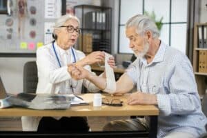 Doctor wrapping bandage on arm of senior man